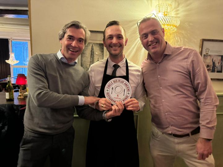 Drie mannen houden lachend samen het schild van de Cercle vast, met in het midden het logo van De Rooden Hoed