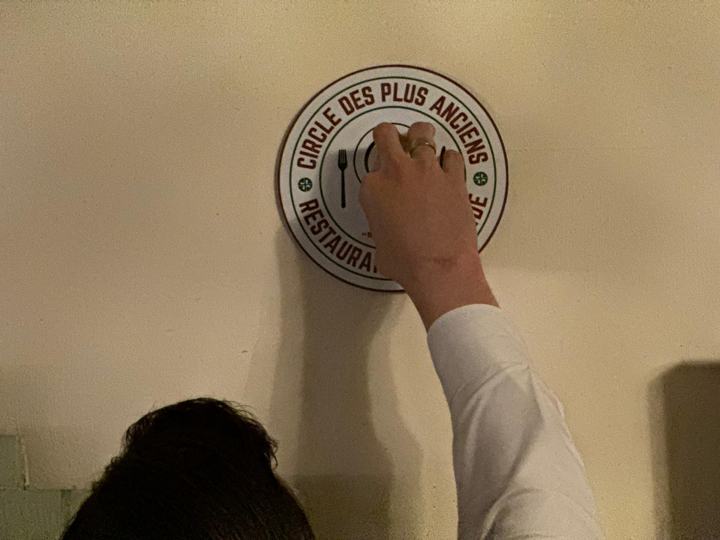 Een hand drukt het schild stevig tegen de wand