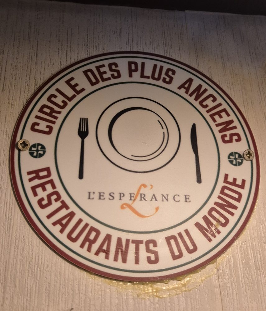 Het ronde schild van de Cercle aan de wand van Café L'Espérance in Leiden